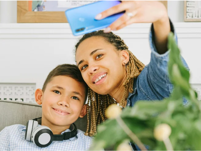 Mother and son smiling while taking a selfie together with a smartphone